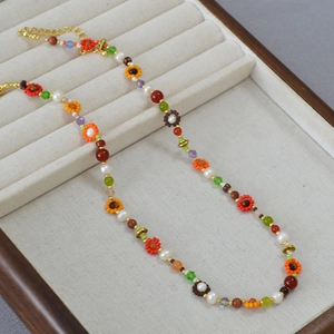 Gros plan d'un collier de perles bohème coloré avec des fleurs sur un fond de velours