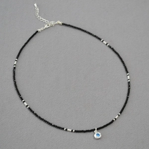 Macro shot of black spinel beaded necklace with a round blue gemstone pendant detail