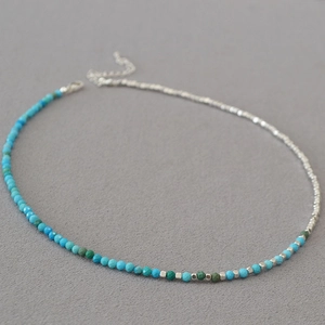 Detail of asymmetric necklace featuring green turquoise beads and silver metal chain link