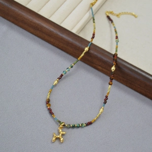 Collier en perles colorées avec pendentif chien ballon doré sur plateau bijoux
