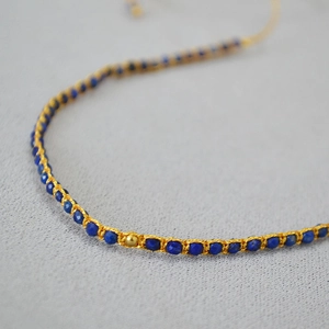 Vue macro d'un bracelet bohème fait main avec perles de lapis et fil doré tressé