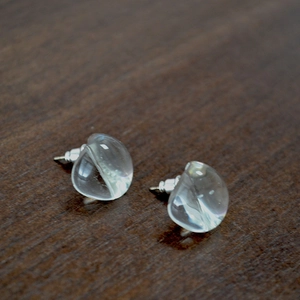 Detailed close-up of transparent glass water drop earrings on a dark wood background