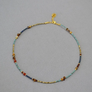 Close-up of colorful beaded necklace with turquoise agate and gold flower pendant