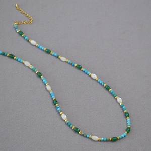 Detail of beaded necklace featuring turquoise, white shells, and gold spacer beads