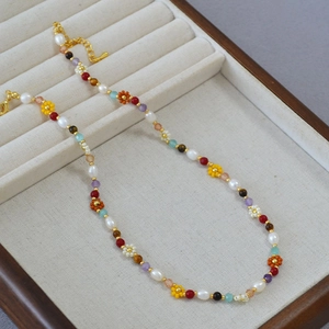 Close-up of handmade daisy beaded necklace with freshwater pearls and gold lobster clasp