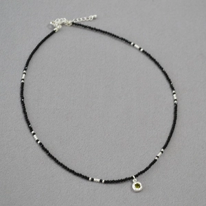 Macro shot of black spinel beads necklace with a green zircon pendant and silver clasp