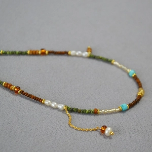 Détail macro d'un collier de perles montrant perles d'eau douce, turquoise et ambre