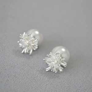 Detail of silver dandelion stud earrings with zircon inlay and large pearl backing