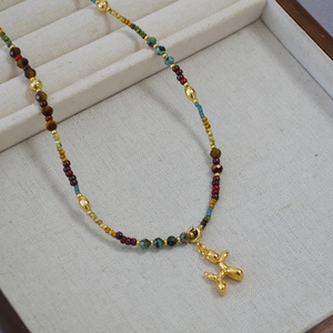 Collier de perles colorées avec un pendentif chien ballon doré en gros plan