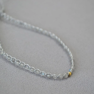 Vue macro d'un bracelet tissé main avec perles de pierre de lune et détail en or