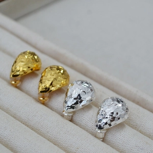 Detail of gold and silver teardrop earrings with textured dragon scale patterns in a box