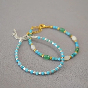 Macro detail of turquoise beaded bracelets with faceted gems and metal lobster clasps