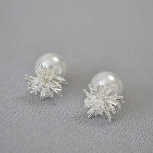 Silver dandelion earrings with cubic zirconia and round pearls on a textured background