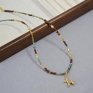 Détail d'un collier de perles colorées avec pendentif chien ballon doré sur plateau bois