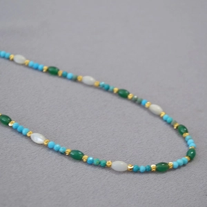 Detail of bohemian necklace with blue turquoise beads, white shells, and gold accents