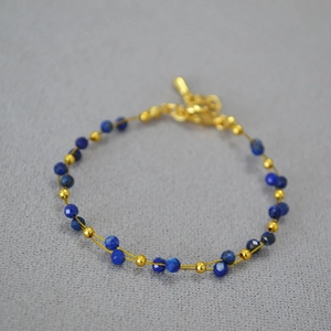 Detail of beaded bracelet featuring lapis lazuli stones and adjustable gold chain