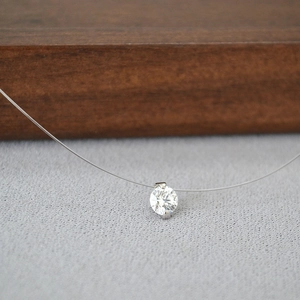 Vue macro du solitaire en zircone sur fil de nylon invisible avec serti griffes argent