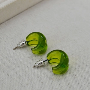 Minimalist green translucent glass C-shaped drop earrings with silver pins on linen