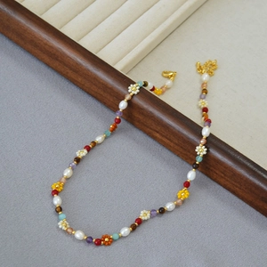Detail of bohemian necklace with baroque pearls, colorful stone beads and beaded flowers