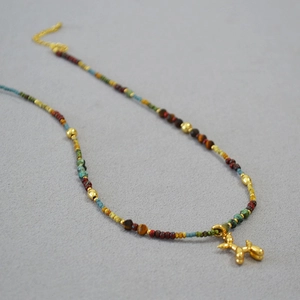 Détail d'un collier de perles colorées avec pendentif chien ballon doré et fermoir homard