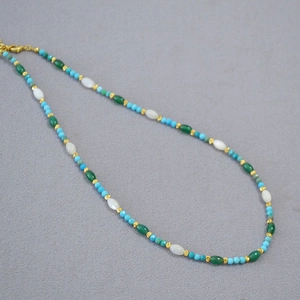 Close-up of beaded necklace with turquoise, white opal beads and gold accents