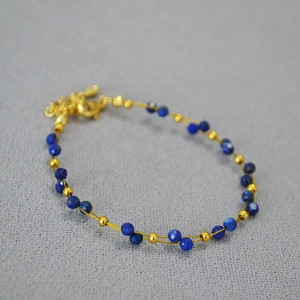 Detail of lapis lazuli beaded double-layer bracelet with golden thread and lobster clasp