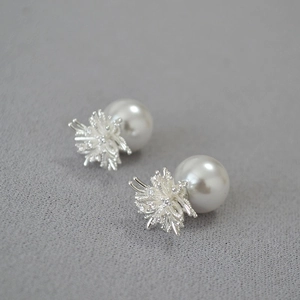 Macro shot of silver dandelion earrings with sparkling crystals and elegant white pearls