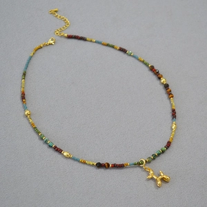 Détail de perles colorées et pendentif chien ballon doré sur collier vintage