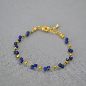 Detail of double-layer gold chain bracelet with blue lapis beads and lobster clasp closure