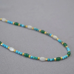 Detail of beaded necklace with blue turquoise, white shell, and green stones