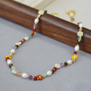 Macro view of handmade beaded necklace with freshwater pearls and colorful floral accents