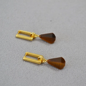 Close-up of vintage gold geometric earrings featuring brown pear-cut tiger eye stones