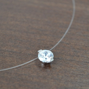Détail d'un pendentif en zircon sur un collier en fil de pêche transparent invisible
