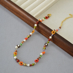 Gros plan du collier de perles bohème avec tournesols oranges et fermoir mousqueton doré