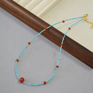 Detail of turquoise tube beads and red agate necklace on a jewelry display tray