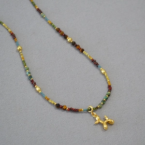 Vue détaillée de perles multicolores et pendentif chien ballon doré poli sur collier
