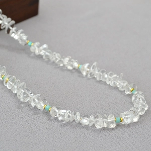 Macro detail of irregular clear quartz and blue beads with golden spacers on fabric