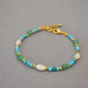 Detail of beaded turquoise bracelet with adjustable gold chain and shell beads