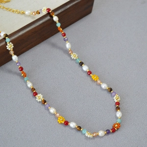Detail of colorful beads, freshwater pearls, and woven flowers on a dainty choker necklace