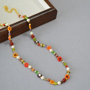 Détail d'un collier bohème en perles Miyuki avec fleurs tissées et accents de perles