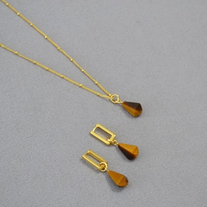 Detailed view of tiger eye stone pendant and earrings on a gold-plated beaded chain