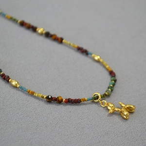 Détail d'un collier de perles colorées avec un pendentif chien ballon en or poli