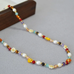 Detail of colorful daisy seed bead necklace with freshwater pearls and gold spacers