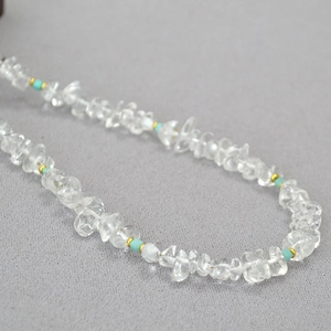 Macro detail of clear quartz fragments and blue amazonite beads on a gold-toned necklace