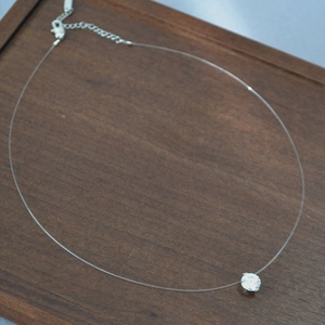 Détail du pendentif en zircon étincelant avec une chaîne invisible en fil de pêche transparent
