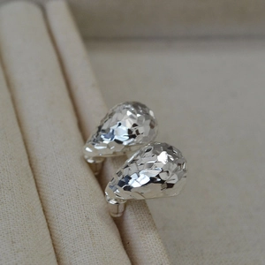 Macro view of silver-tone teardrop earrings featuring a shimmering geometric dragon scale texture
