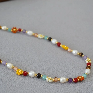 Detail of beaded necklace featuring freshwater pearls and multi-colored daisy flower charms