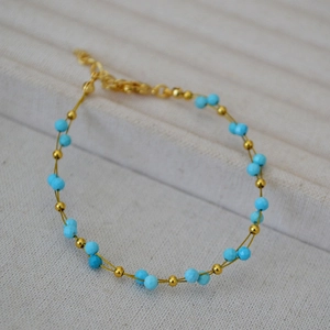 Macro detail of double-layer gold beaded bracelet with turquoise stones and adjustable clasp