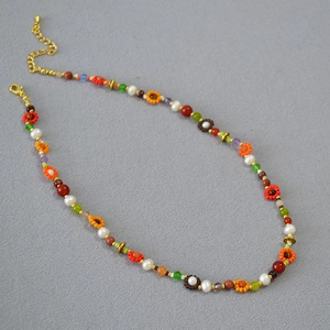 Détail du collier bohème perlé coloré avec motifs floraux et fermoir mousqueton doré