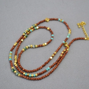Vintage beaded necklace with goldstone turquoise and a small cross pendant on fabric